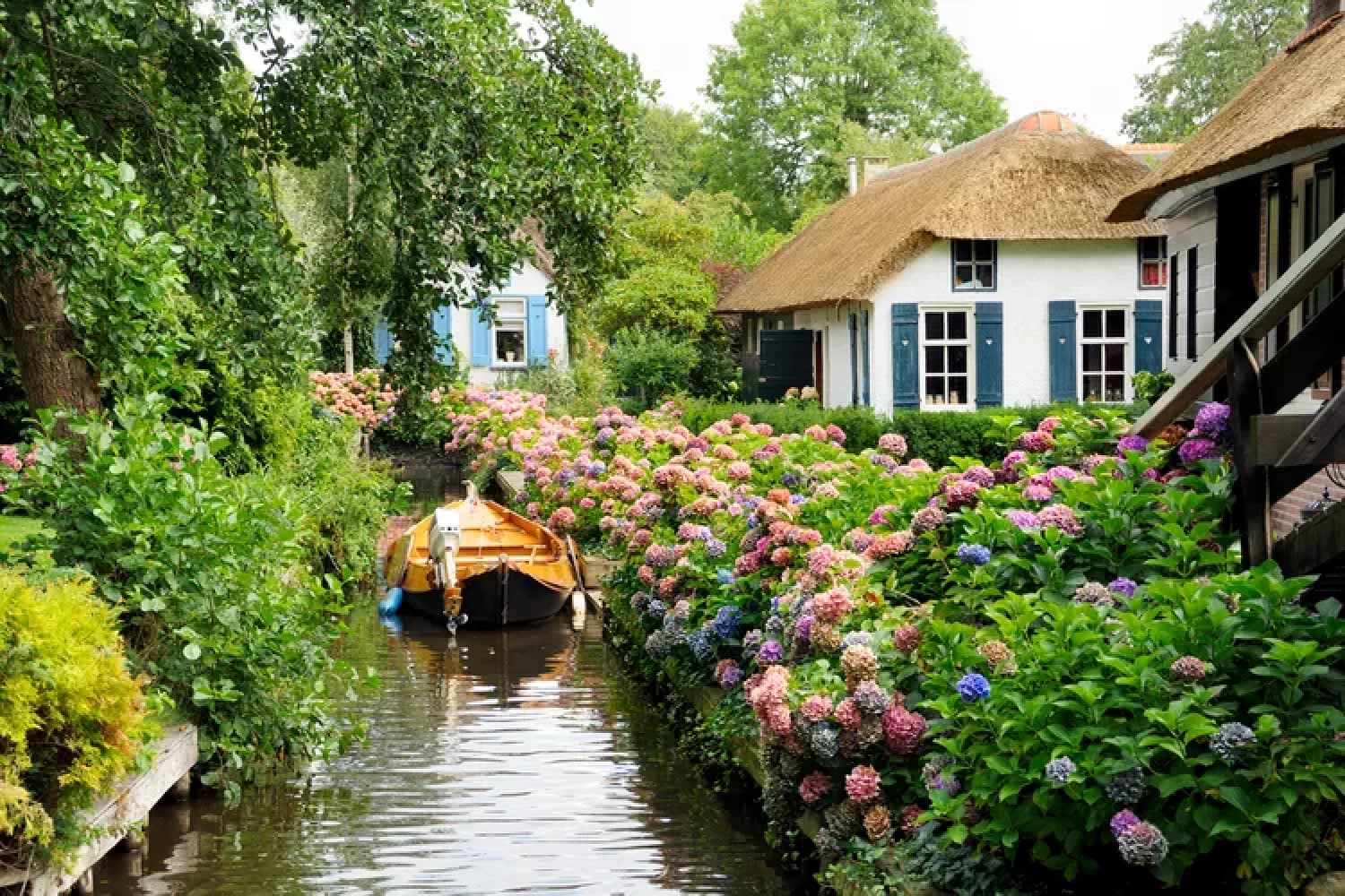 Narrow water alley between traditional houses in Giethoorn